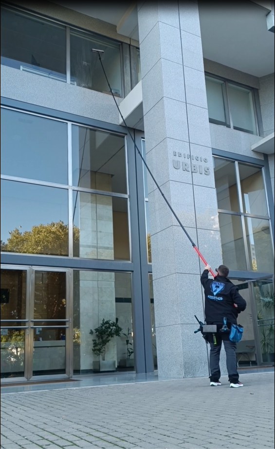 Operario limpiando cristal exterior en altura
